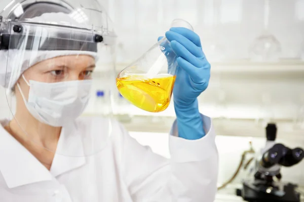 Closeup portrait female scientist holding conical tube with liquid solution, laboratory experiments, isolated lab background. Forensics, genetics, microbiology, biochemistry.