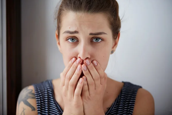 Frustrated stressed young woman. Headshot unhappy overwhelmed girl having headache bad day keeps hands on face out isolated on wall background. Negative emotion face expression feelings perception.