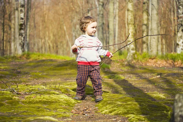 The child with the sticks to walk.