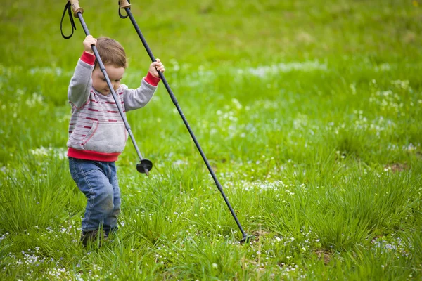 The child with the sticks to walk.