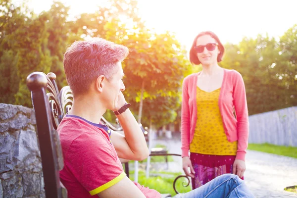 A man sits on a bench and talking on the phone while his girl was.