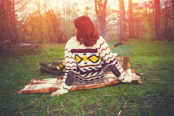 The girl in a warm sweater sitting by the fire.