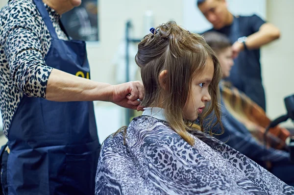 Barber cutting long hair of a girl