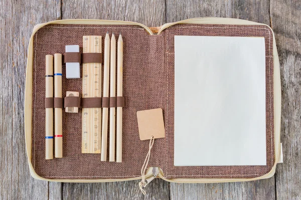 Open notebook on wooden background with wooden ruler and pencils