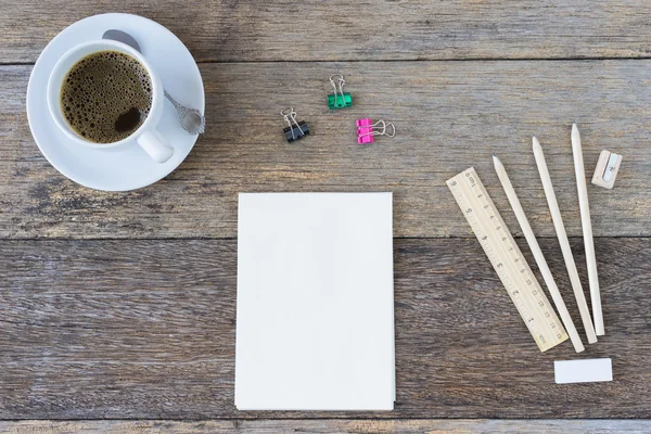 Open notebook on wooden background with coffee cup.