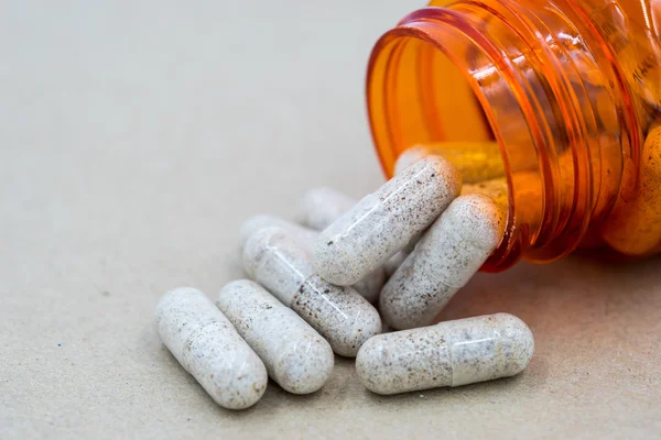 Herb capsules spilling out of a bottle.