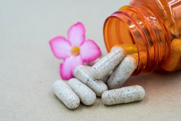 Herb capsules spilling out of a bottle.