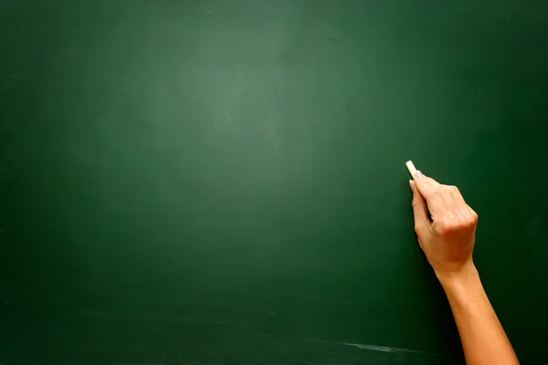 Female teen hand to draw something on blackboard with chal