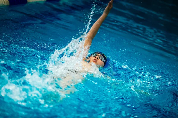 Young male athlete swimming backstroke