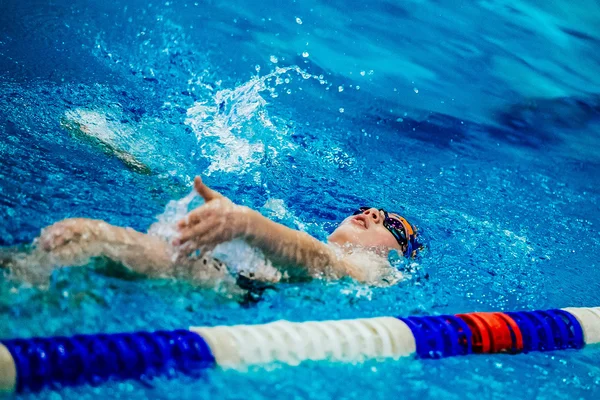 Young athlete swimming backstroke