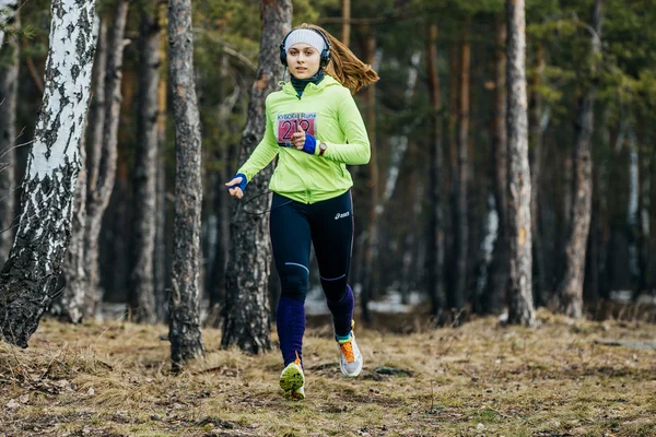 Young girl athlete running in a spring forest