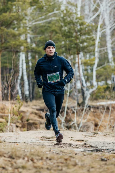 Young male athlete runs in a spring forest