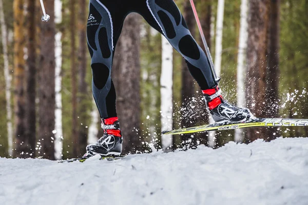 Feet men skier sprays snow from under ski
