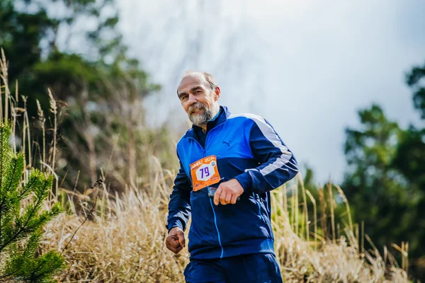 Elderly man athlete running on hill