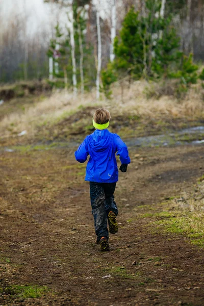 Little boy runs along trail from mountain