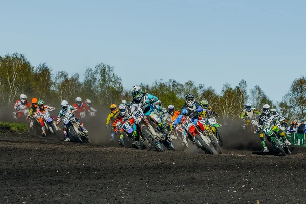 Group of riders motorcycle rides on dusty track
