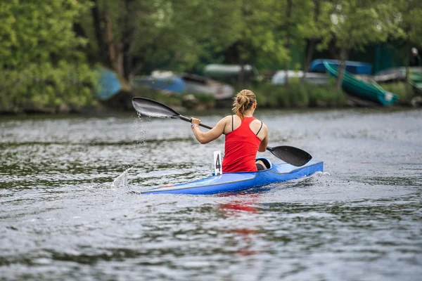 Woman athlete at rowing kayak on lake during competition