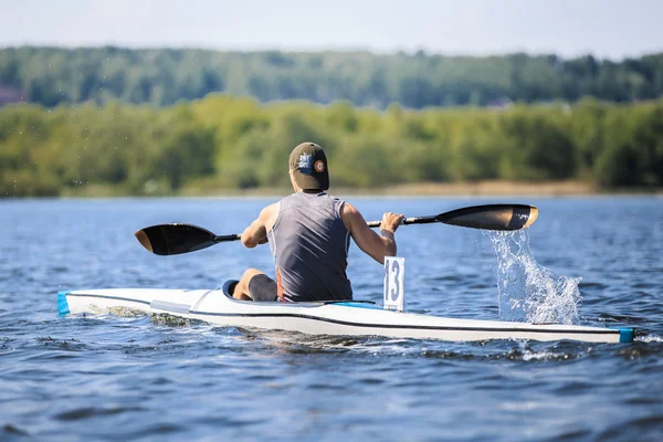 Athlete rower on rowing kayak on lake