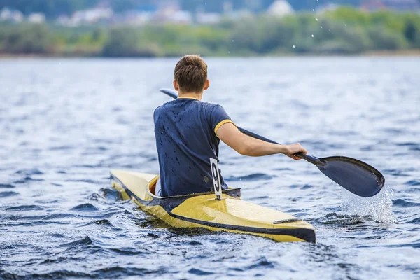 Young man in a canoe rowing oars