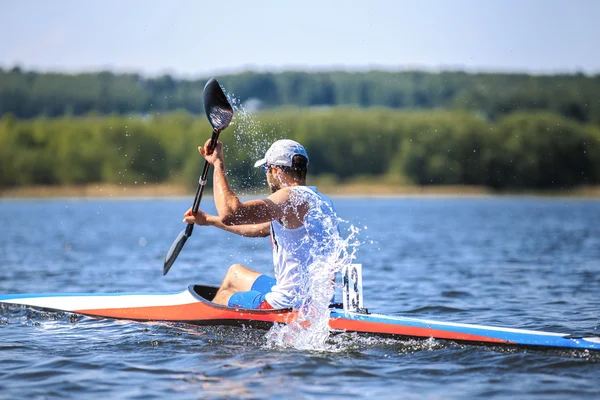 Athlete at rowing kayak on lake