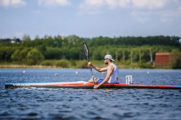 Man athlete rower on rowing kayak on lake