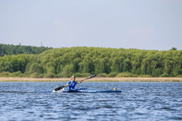 Young man athlete on rowing kayak on lake