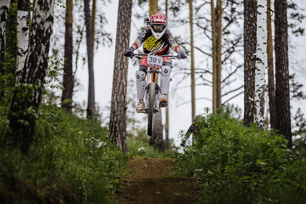 Athlete racer bike jump with a mountain in forest on helmet video camera