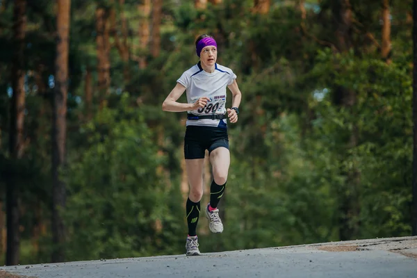 Female athlete running on road in forest
