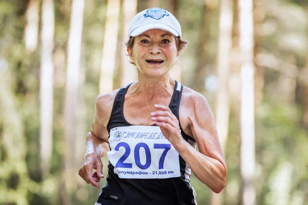 Old woman runs through forest and smiling