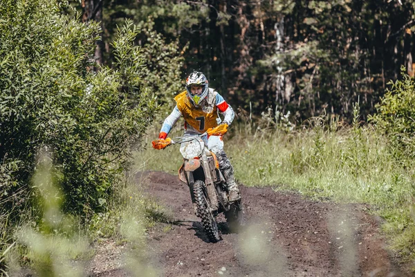 Racer on a motorcycle rides on a dirt track race in forest during Ural Cup in Enduro