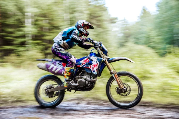 Male athlete motorcycle racer rides in woods during Ural Cup in Enduro