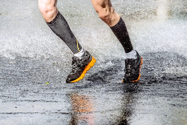 Athlete foot men running through a puddle spray