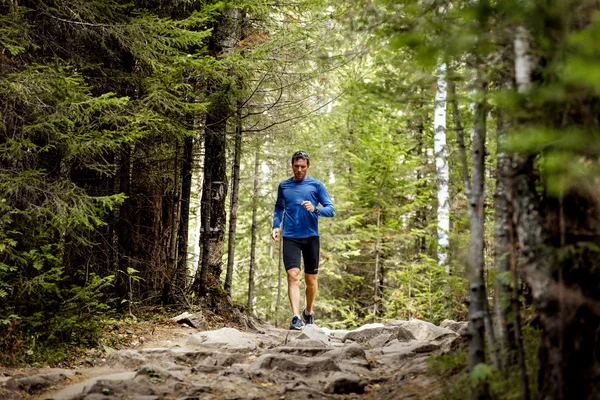 Young male athlete active runs rocks trail in woods