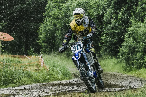 Motocross driver on wet and muddy terrain