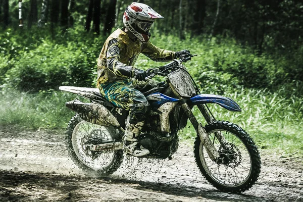Motocross driver on wet and muddy terrain