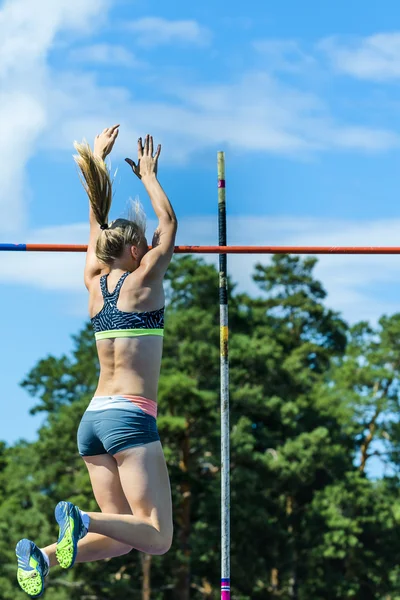 Girl athlete competing in the pole vault at a track and field competition