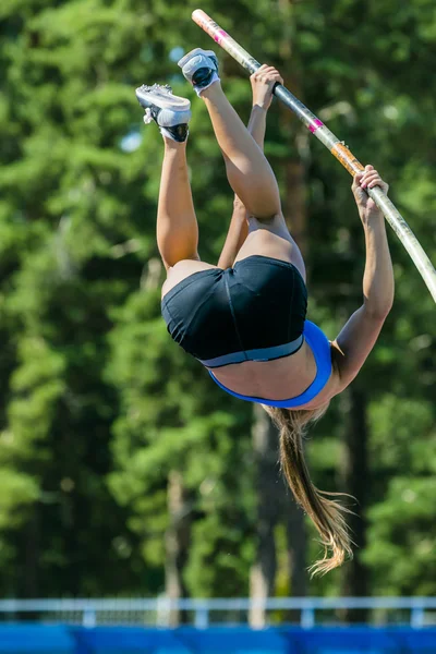 Girl athlete competing in the pole vault at a track and field competition