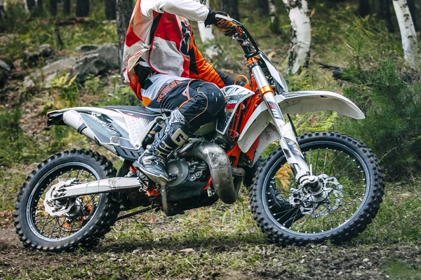 Enduro racer is riding through the woods