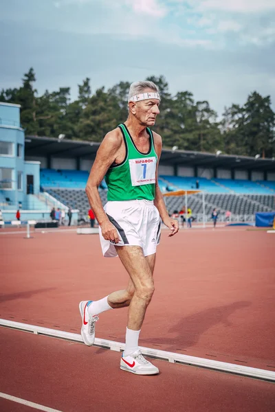 Very old athlete running down the track stadium
