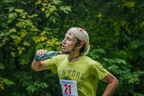 Young runner drinks water from a bottle