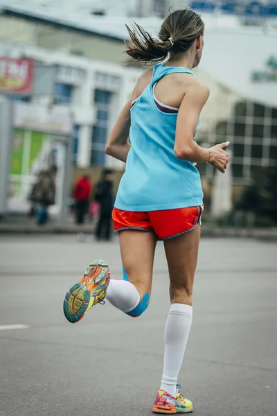 Young girl running a marathon, knees in blue kinesiology taping