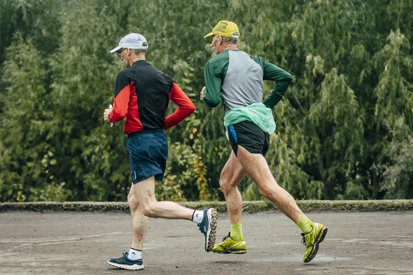 Two elderly athlete run along river