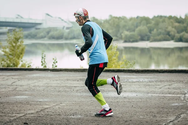 Elderly male runner runs along river