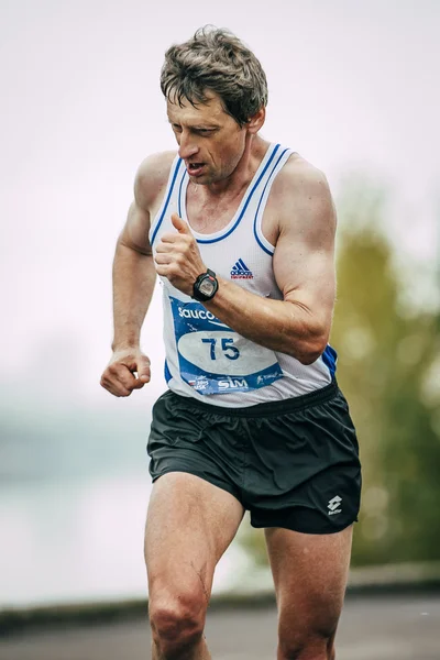 Man middle-aged runner runs along river