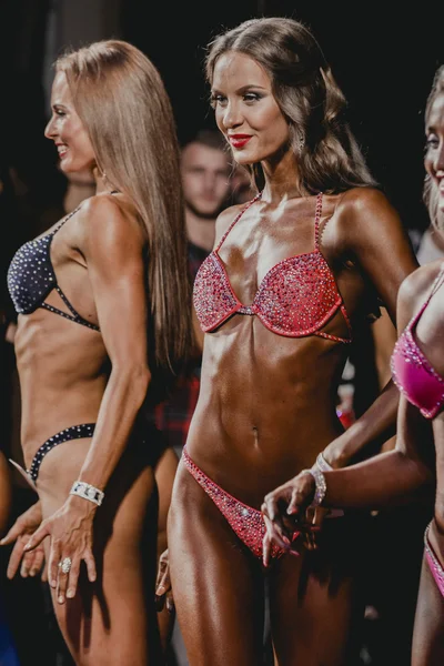 Two bright brunette girls fitness bikini on stage