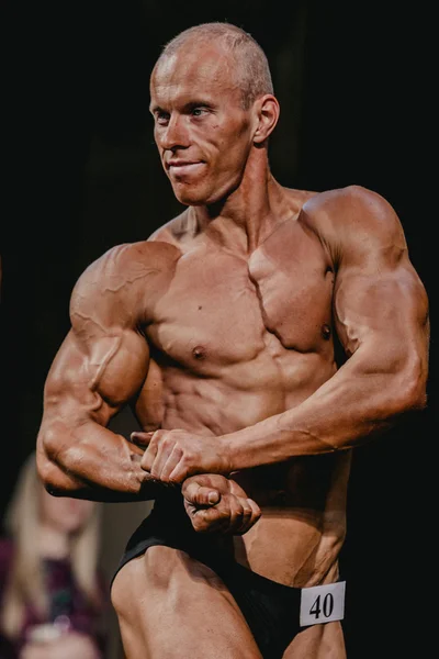 Athlete bodybuilder straining biceps, side view