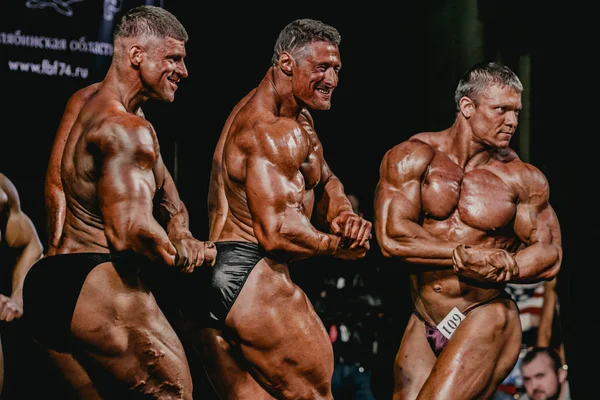 Group of men bodybuilder side view showing biceps of his arms
