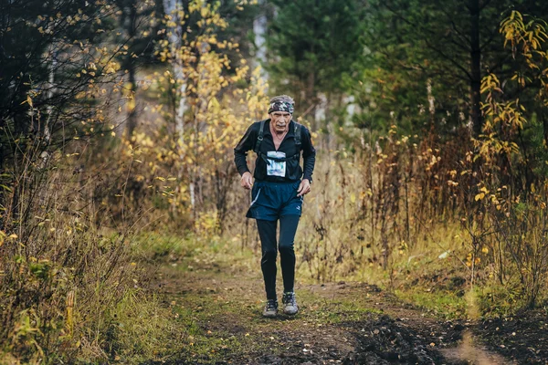 Very old man athlete running in autumn forest