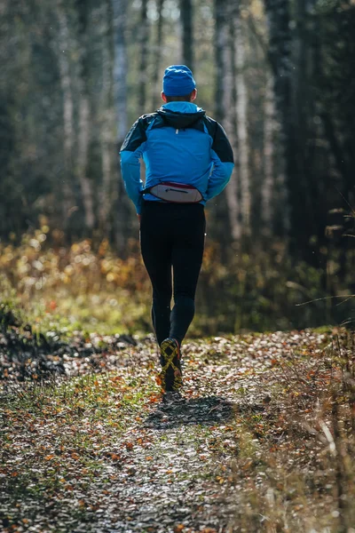 Male runner running through forest