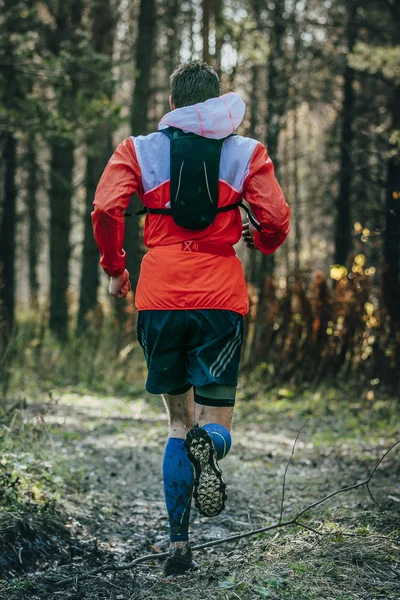 Male runner running through forest